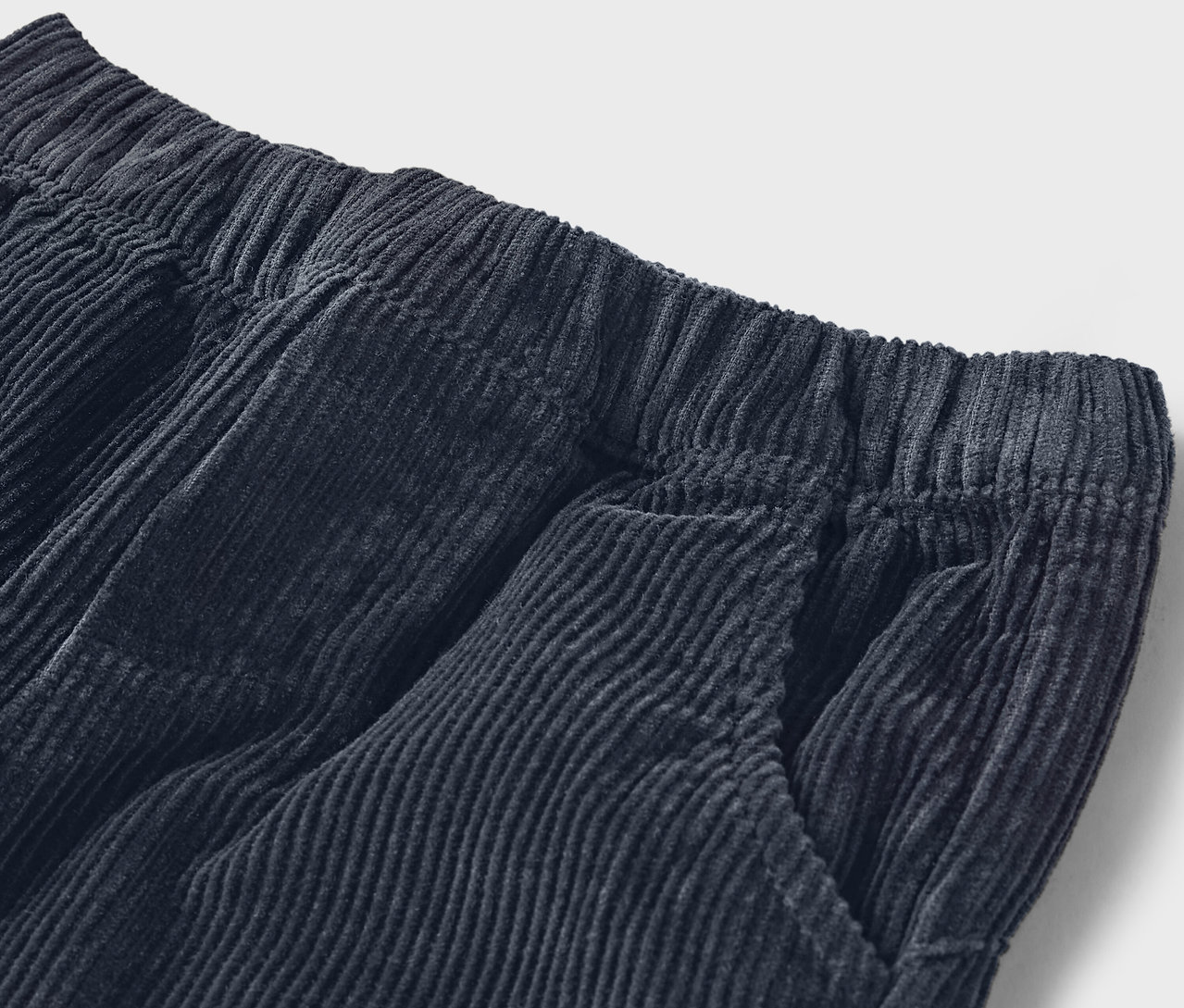 Detail einer marineblauen Cordhose mit elastischem Bund und Tasche.