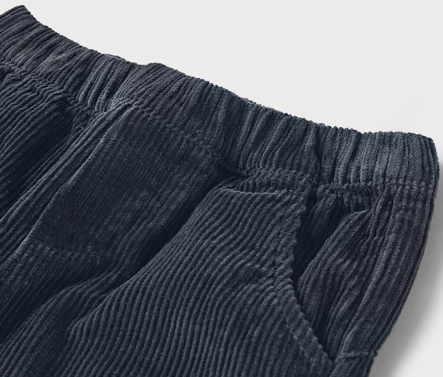 Detail einer marineblauen Cordhose mit elastischem Bund und Tasche.