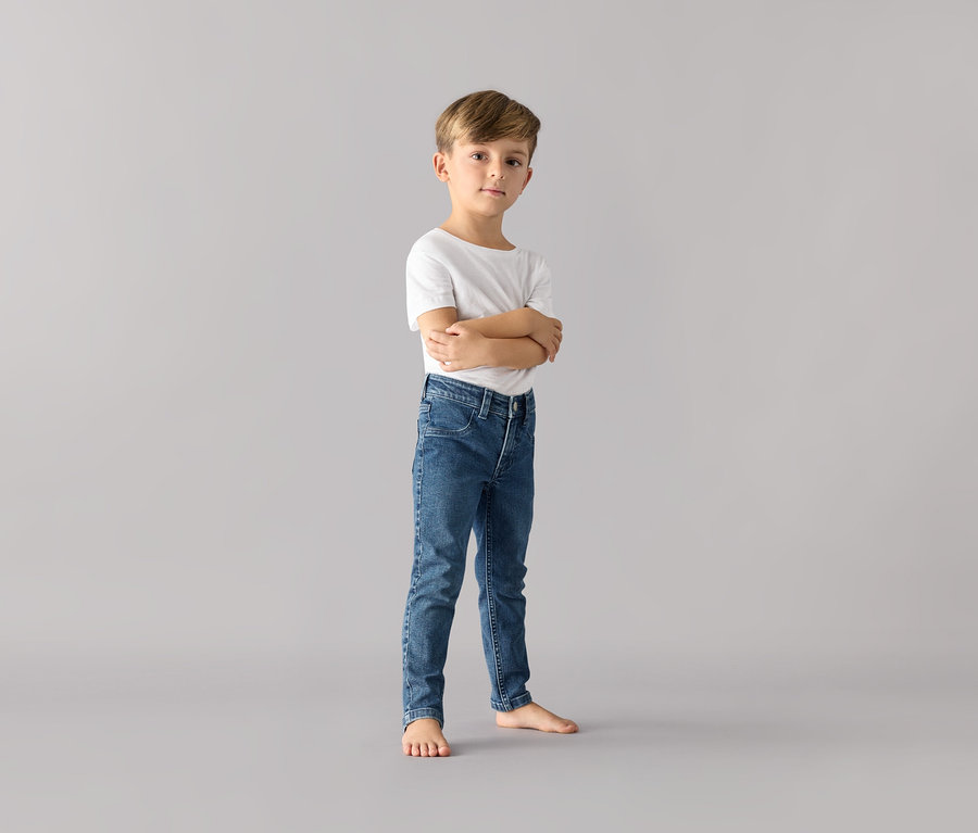 Ein Junge steht mit verschränkten Armen und trägt eine Kinder-Jeans – Fit »Jonas« und ein weißes T-Shirt.
