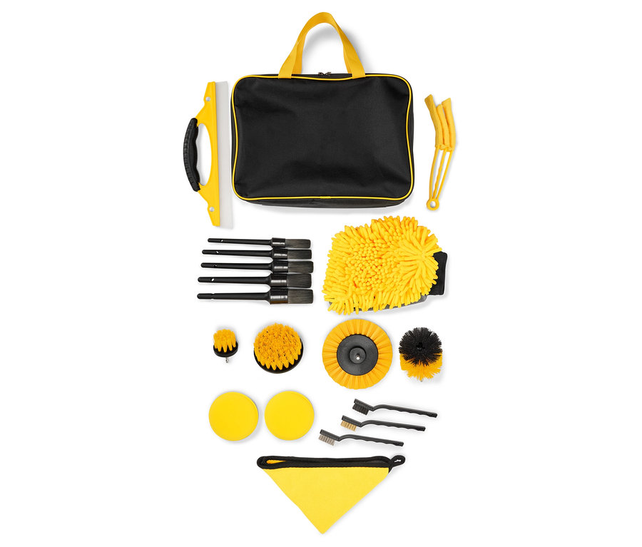 Ein Autoreinigungsset mit einer schwarzen Tasche mit gelben Griffen, einem gelben Waschhandschuh und verschiedenen Bürsten.