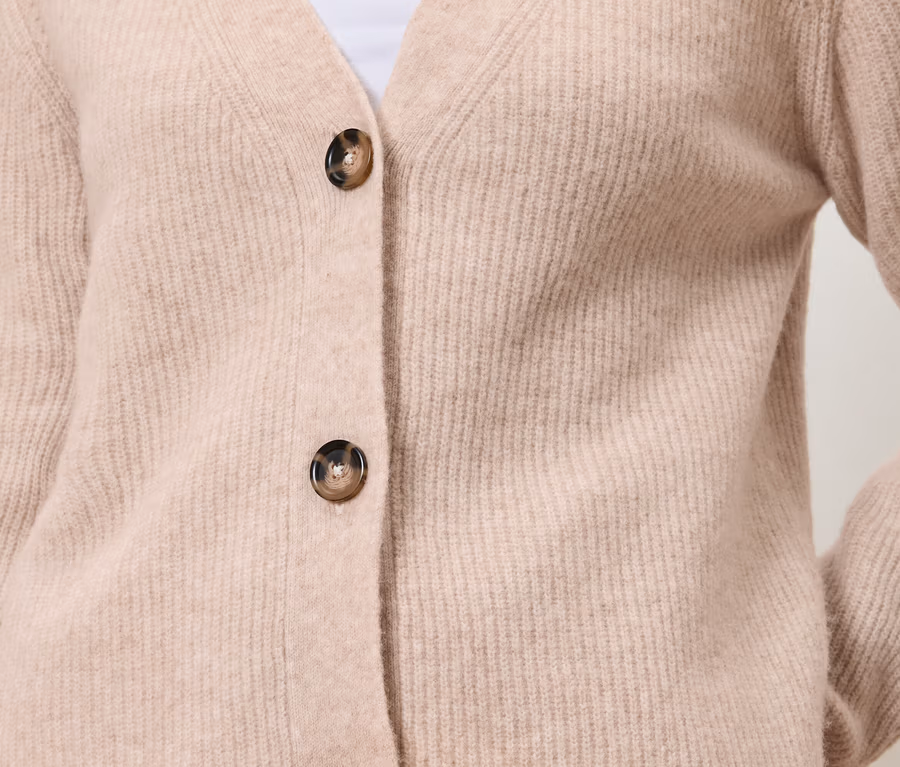 Nahaufnahme einer hellrosa Strickjacke mit zwei Knöpfen und V-Ausschnitt.