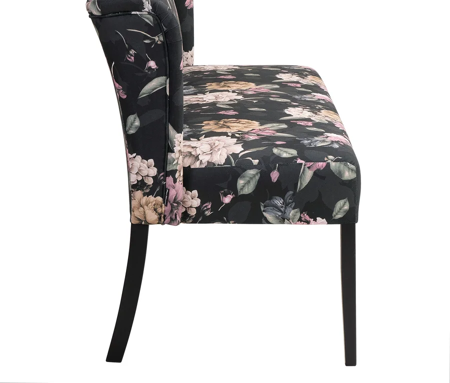 Seitenansicht eines floral gemusterten Polstersessels mit dunklen Holzbeinen.