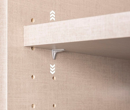 Nahaufnahme einer hellen Regalbodenbefestigung mit einem silbernen Winkelverbinder an einer beigen Wand mit Löchern.