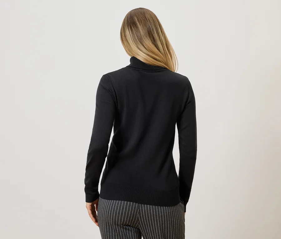 Rückansicht einer Frau mit blonden Haaren, die einen schwarzen Rollkragenpullover und eine grau gestreifte Hose trägt.