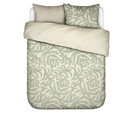 Draufsicht auf ein Bett mit hellbeiger Bettwäsche und einem Kissen mit grünem Farnmuster.