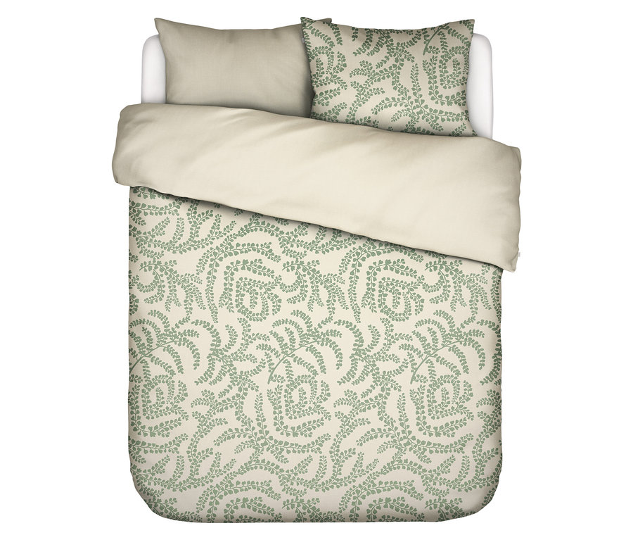 Draufsicht auf ein Bett mit hellbeiger Bettwäsche und einem Kissen mit grünem Farnmuster.