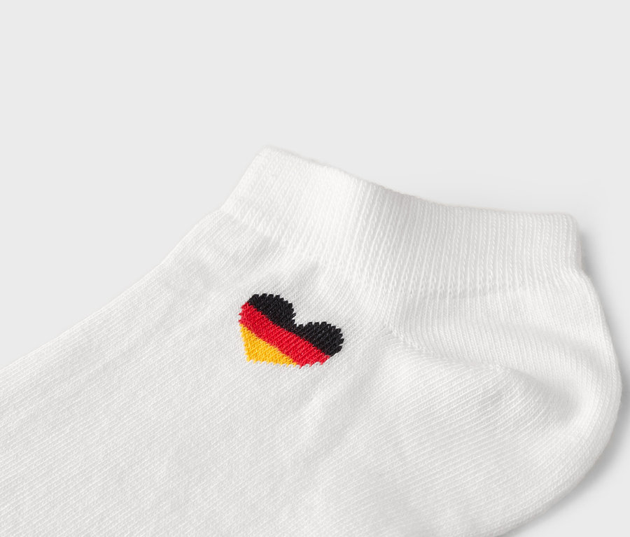 Nahaufnahme einer weißen Socke mit einem herzförmigen deutschen Flaggensymbol.