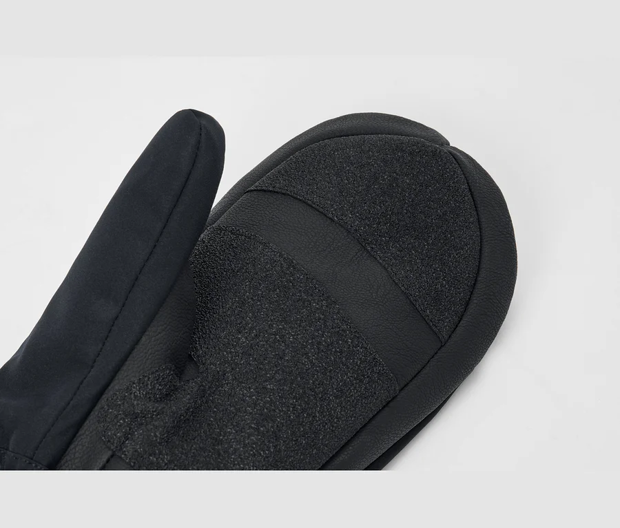 Nahaufnahme eines schwarzen Fäustlings mit strukturierter Handfläche, die zwei Bereiche aus körnigem Griffmaterial, getrennt durch einen glatten Streifen, aufweist.