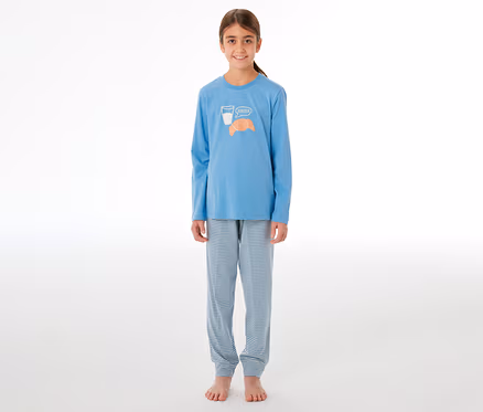 Lächelndes Mädchen in einem SCHIESSER Kinder-Pyjama. Das hellblaue Oberteil hat ein Glas Milch, ein Croissant und "Bonjour" aufgedruckt. Die Hose ist hellblau-weiß gestreift.
