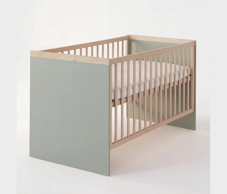 Babybett mit hellgrünen Paneelen, Naturholzstäben und einer weißen Matratze.