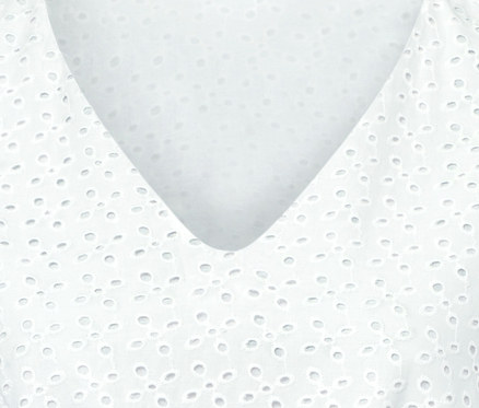 Detailansicht eines weißen Kleides mit Lochstickerei.