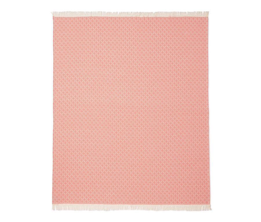 Eine peachfarbene Wohndecke mit geometrischem Muster und Fransen.