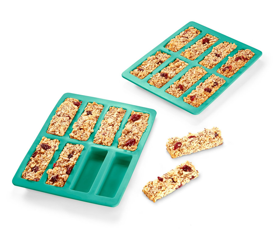 Zwei Müsliriegel-Backformen, eine voll und eine mit einigen Riegeln daneben auf weißem Hintergrund.