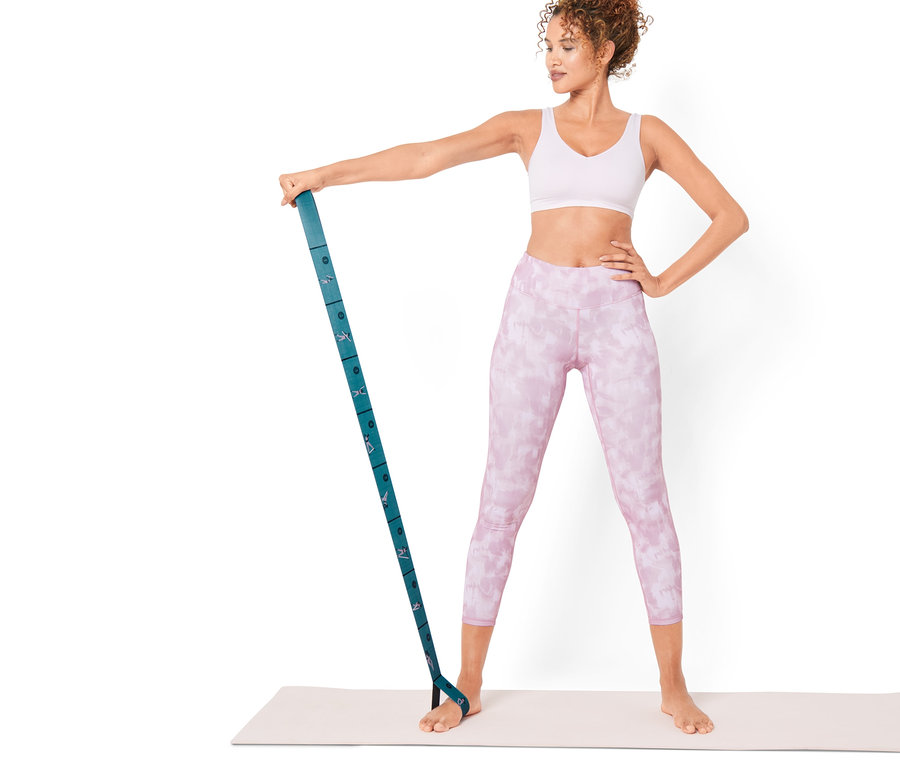 Frau steht auf einer Matte und trainiert mit einem Fitness-Elastikband.