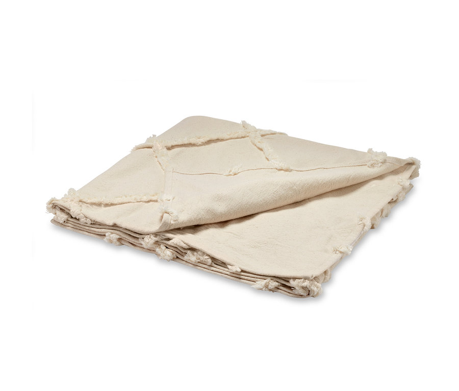 Gefaltete, cremefarbene Wohndecke mit Fransen.