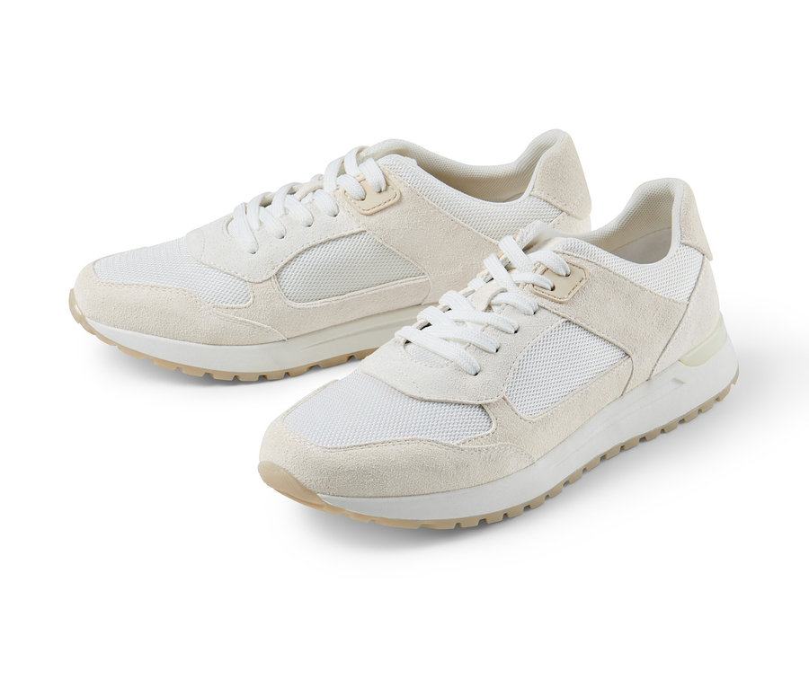 Zwei cremefarbene Veloursleder-Sneaker liegen auf einem weißen Hintergrund.