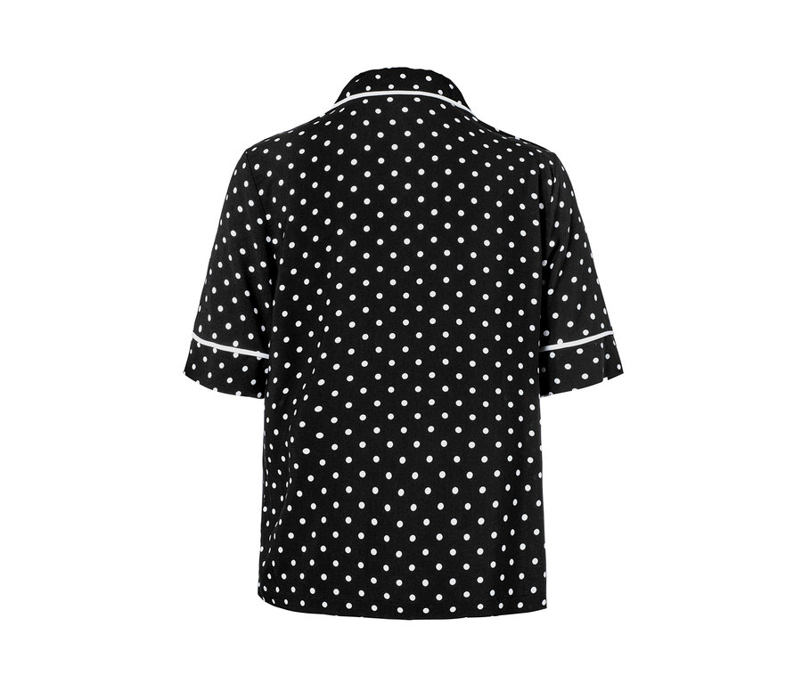 Detailansicht eines Shorty-Pyjamas mit schwarzem Hintergrund und weißen Punkten.