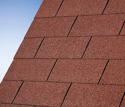 Nahaufnahme von rotbraunen Dachschindeln vor blauem Himmel.