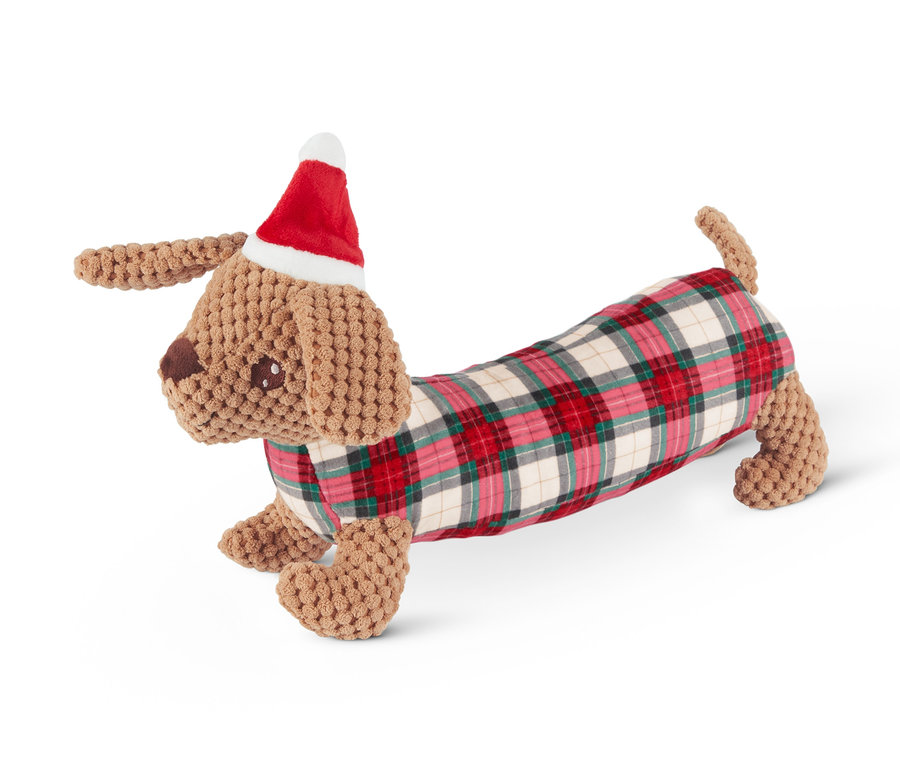 Ein Dackel-förmiges Hunde-Spielzeug mit Weihnachtsmütze und karierter Decke.