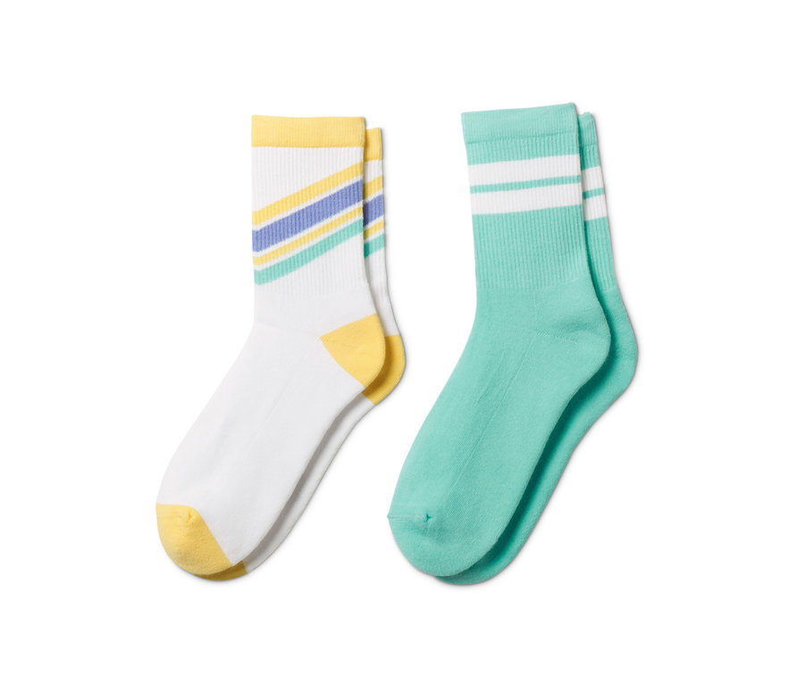 Zwei Paar Tennissocken mit Bio-Baumwolle. Ein Paar ist weiß mit gelben Details und farbigen Streifen, das andere Paar ist türkis mit weißen Streifen.