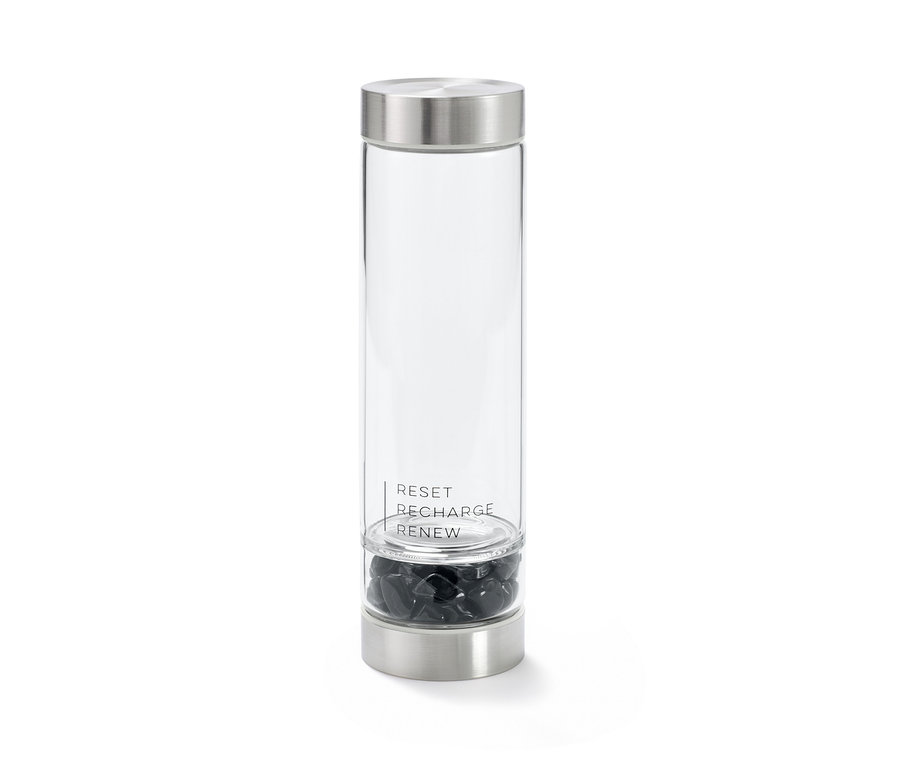 Eine Obsidian-Trinkflasche mit silbernem Deckel und Boden. Im Inneren befinden sich schwarze Obsidiansteine. Auf der Flasche steht: RESET, RECHARGE, RENEW.
