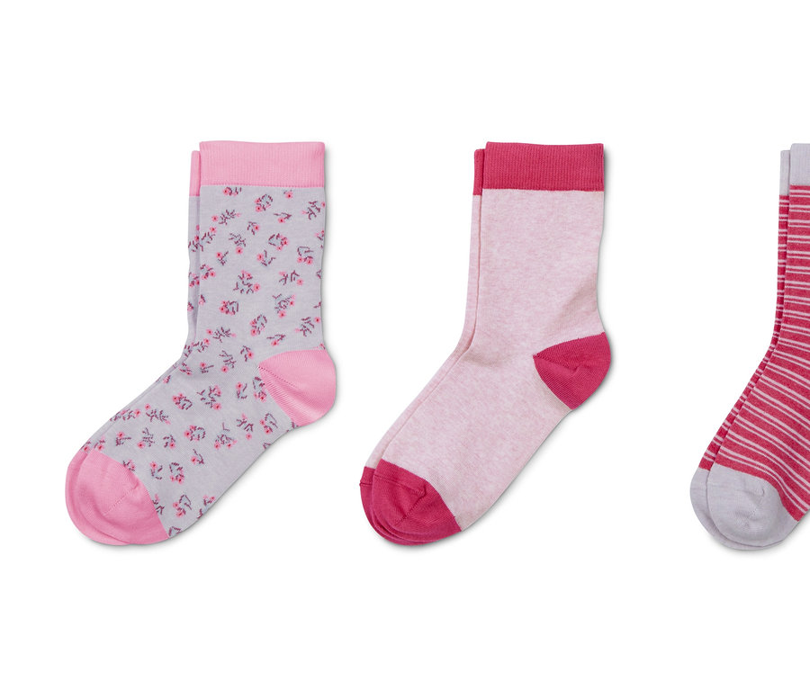 Drei Paar Socken: ein Paar grau mit rosa Blumen, ein Paar hellrosa und ein Paar weiß-rosa gestreift.