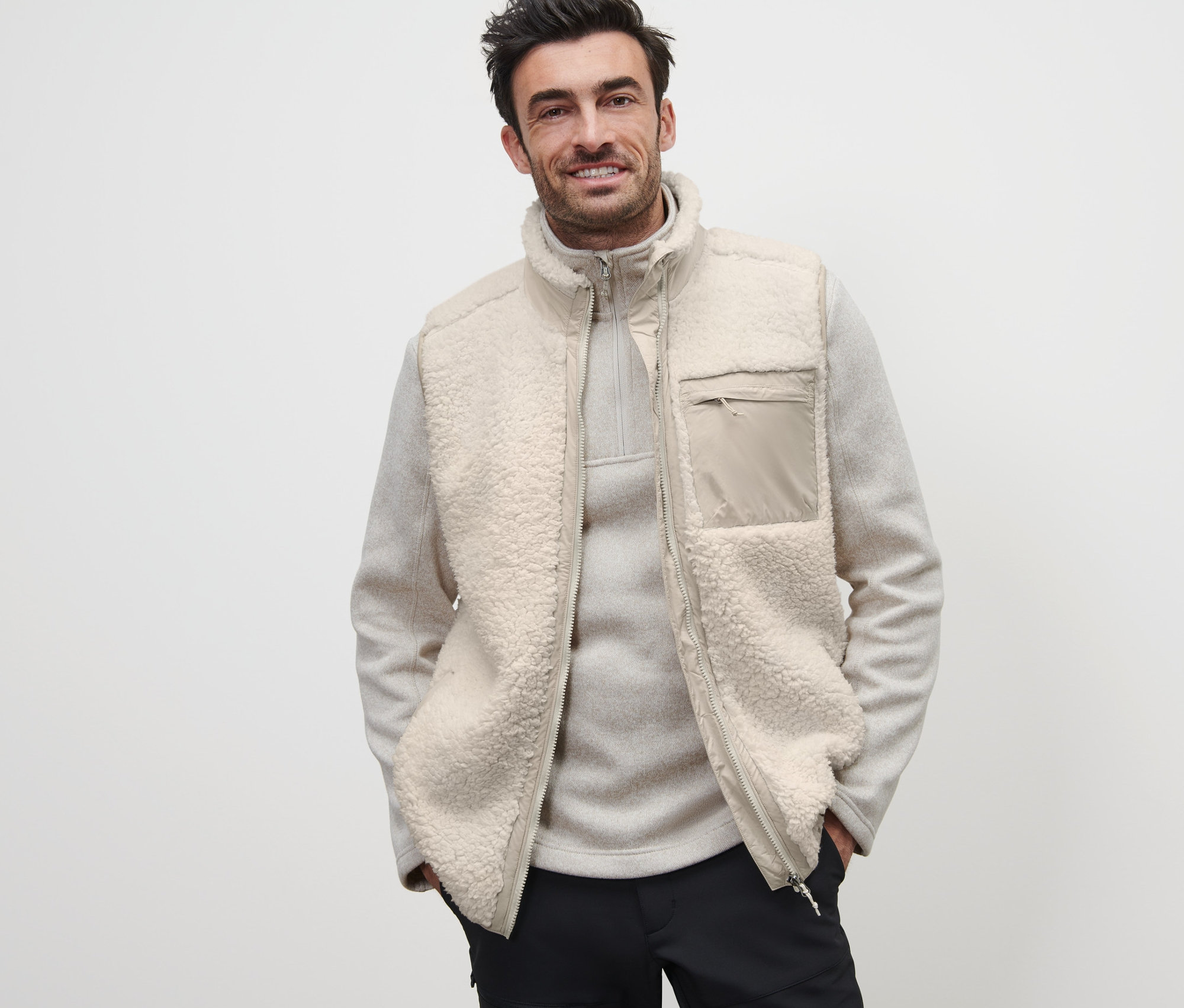 Mann trägt eine Teddy-Weste über einem hellen Pullover mit Reissverschluss.