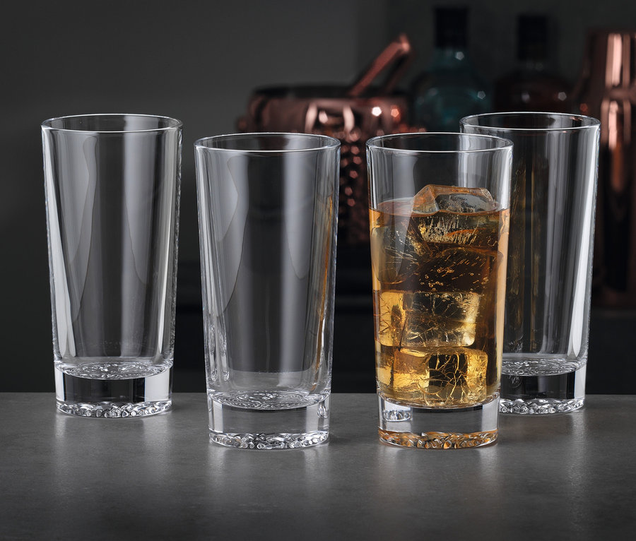 Vier Spiegelau Longdrinkgläser »Lounge 2.0« stehen auf einer Bar, eines davon mit Getränk und Eiswürfeln.