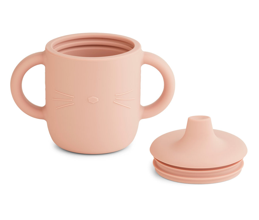 Ein rosafarbener Liewood 2 Trinkbecher mit Henkeln und Katzenmotiv steht neben einem Deckel.