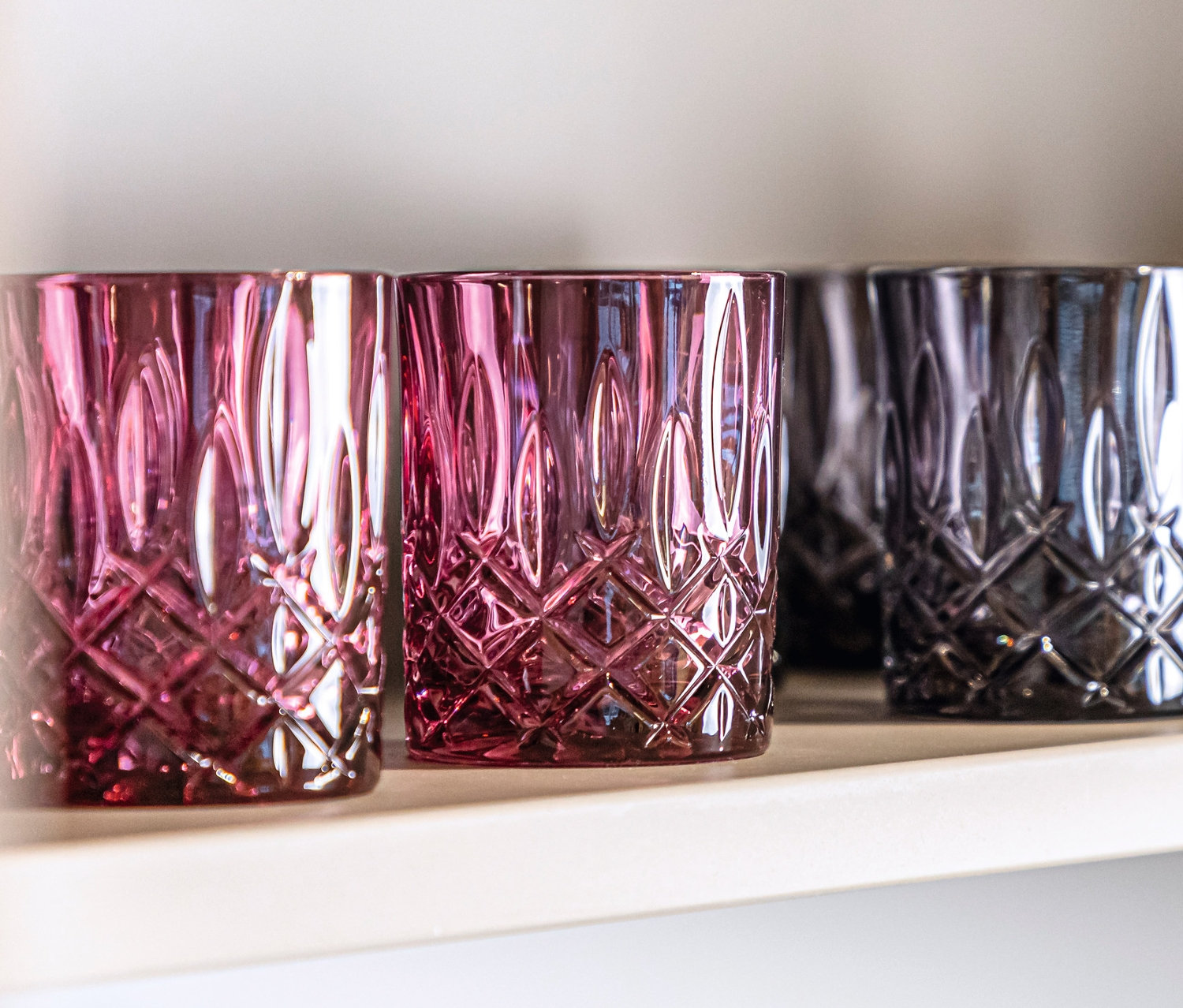 Auf einem Regal stehen Nachtmann Tumbler »Noblesse« Gläser in den Farben Berry und Smoke.