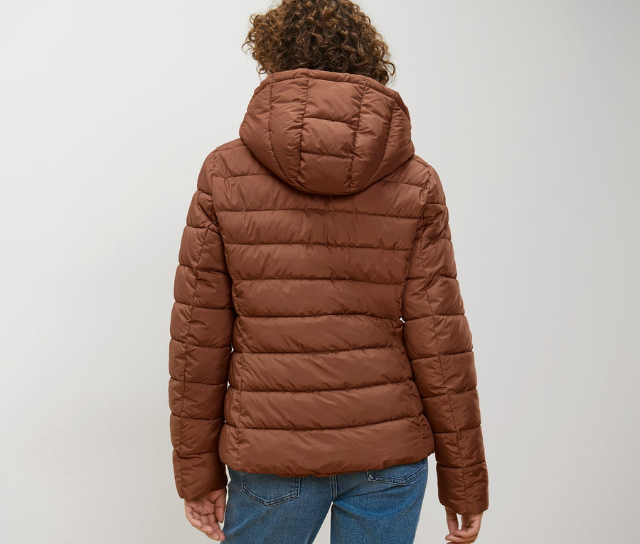 Rückansicht einer Frau, die eine cognacfarbene Steppjacke mit Kapuze trägt.