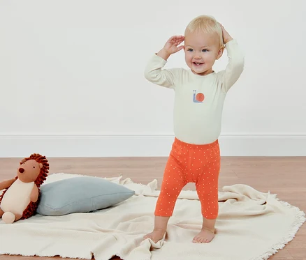 Ein Kind steht auf einer Decke und trägt eine 3/4-langen Baby-und-Kleinkinder-Leggings (4 Stück).