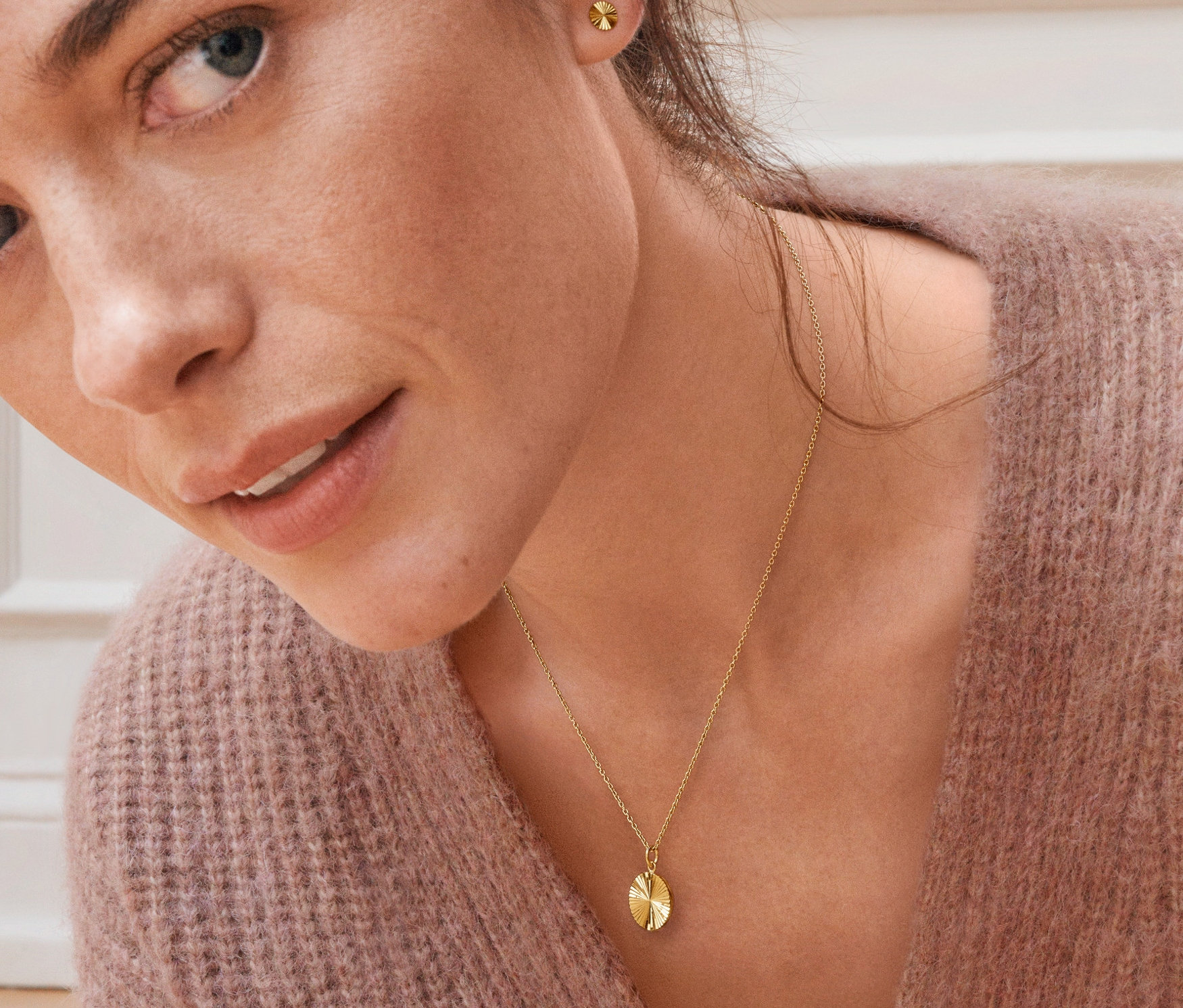 Porträt einer Frau mit Ohrsteckern und Kette aus 925er Silber vergoldet mit Sonnenschliff.