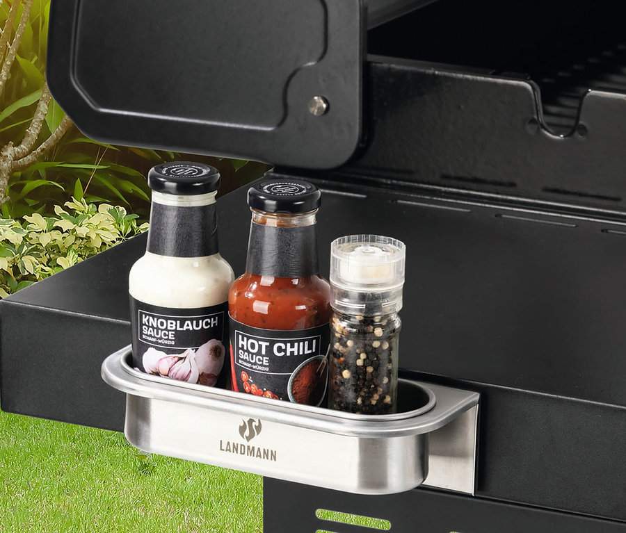 Drei Flaschen mit Soßen stehen in einem magnetischen Landmann Zubehör am Grill.