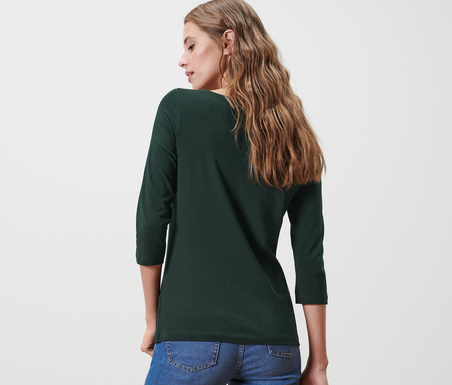 Rückansicht einer Frau in einem grünen Shirt mit 3/4-Arm und blauen Jeans.