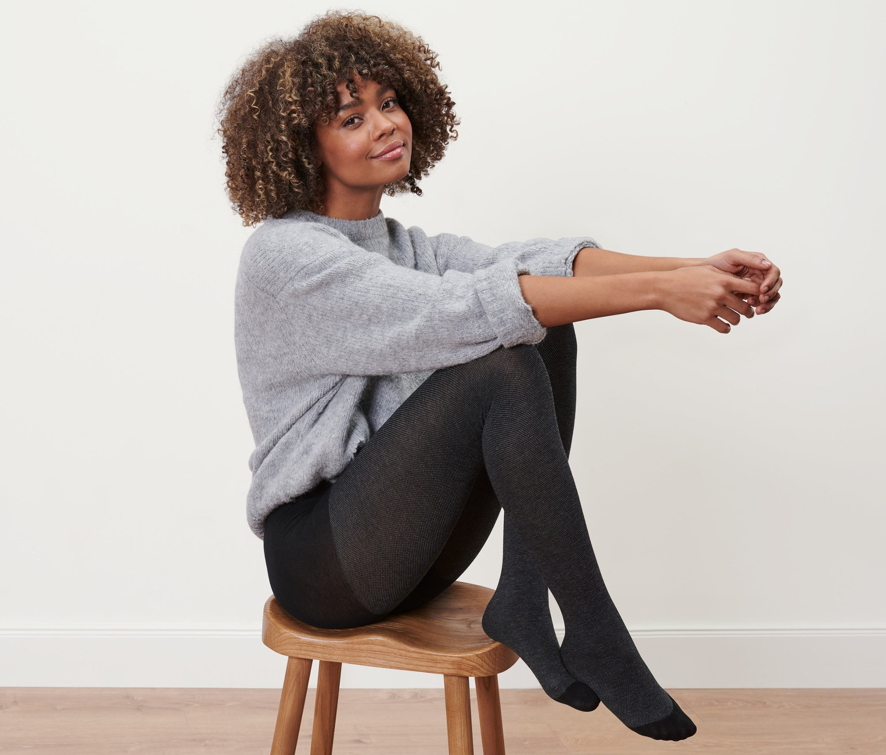 Frau sitzt auf einem Hocker und trägt eine Struktur-Strumpfhose.