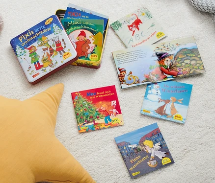 Auf einem weißen Teppich liegen ein Plüschhund, ein gelber Stern und Pixi-Bücher. Eine Bücherbox: »Pixis beste Weihnachtsdose« und mehrere Pixi-Bücher sind verstreut.