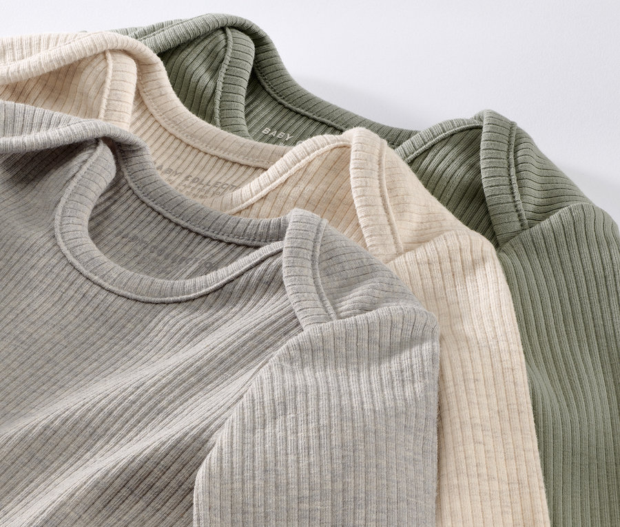 Detailaufnahme von drei gerippten Baby-Shirts in Grau, Creme und Olivgrün.