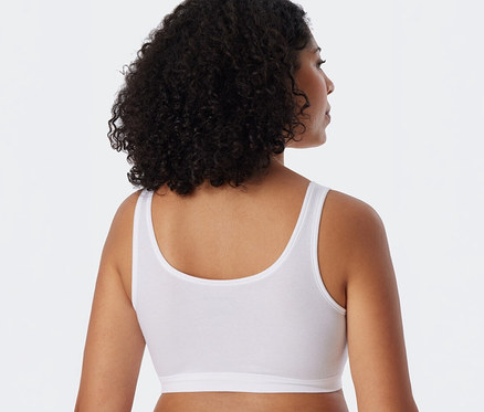 Frau von hinten, den Kopf leicht nach rechts gedreht, trägt ein weißes SCHIESSER Bustier.