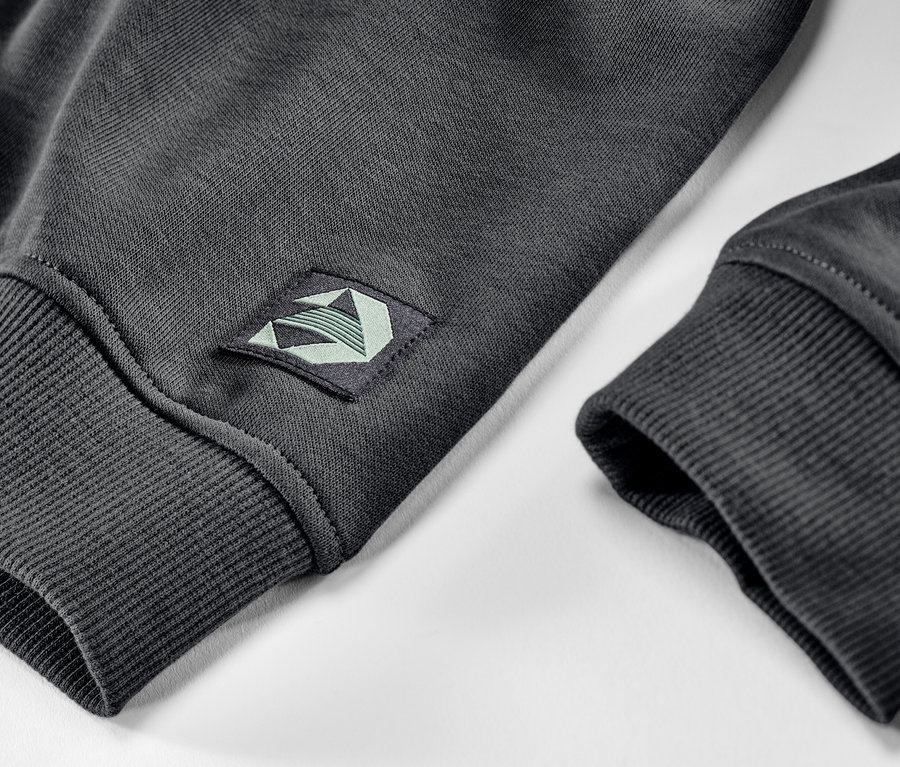 Detailansicht einer Kinder-Sweatjacke mit angerauter Innenseite und einem Aufnäher auf dem Ärmel.