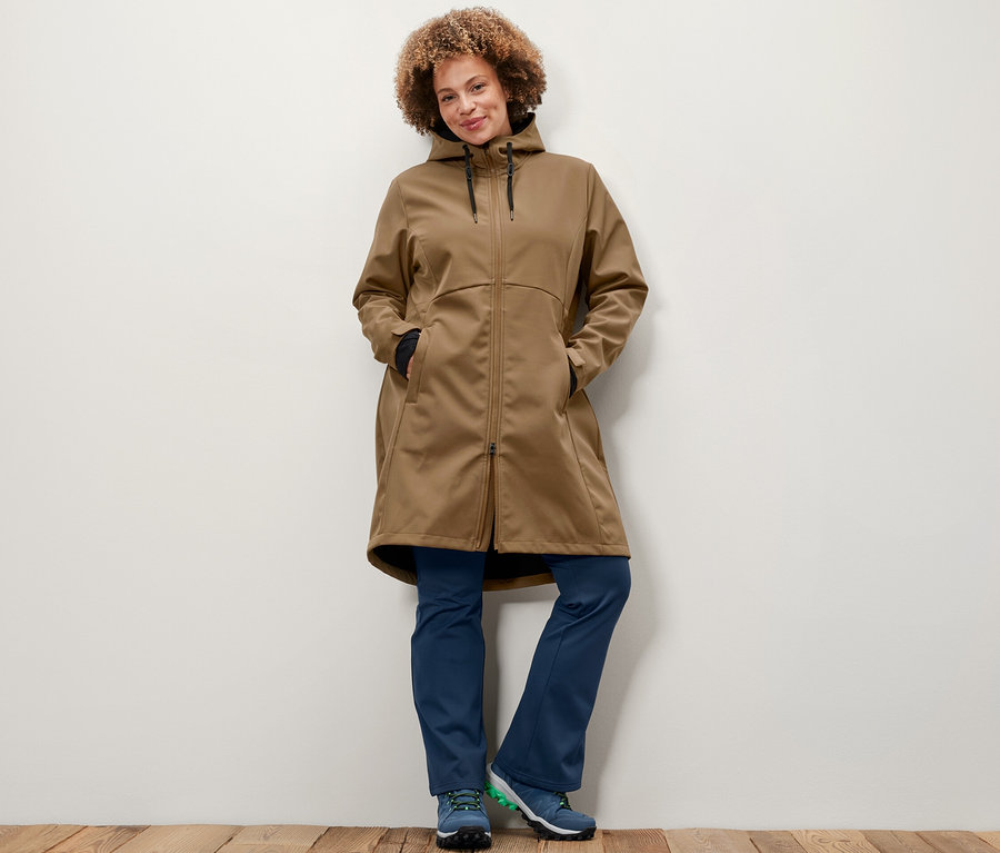 Frau posiert in Softshellmantel in Nougatfarbe und Thermo-Jazzpants.