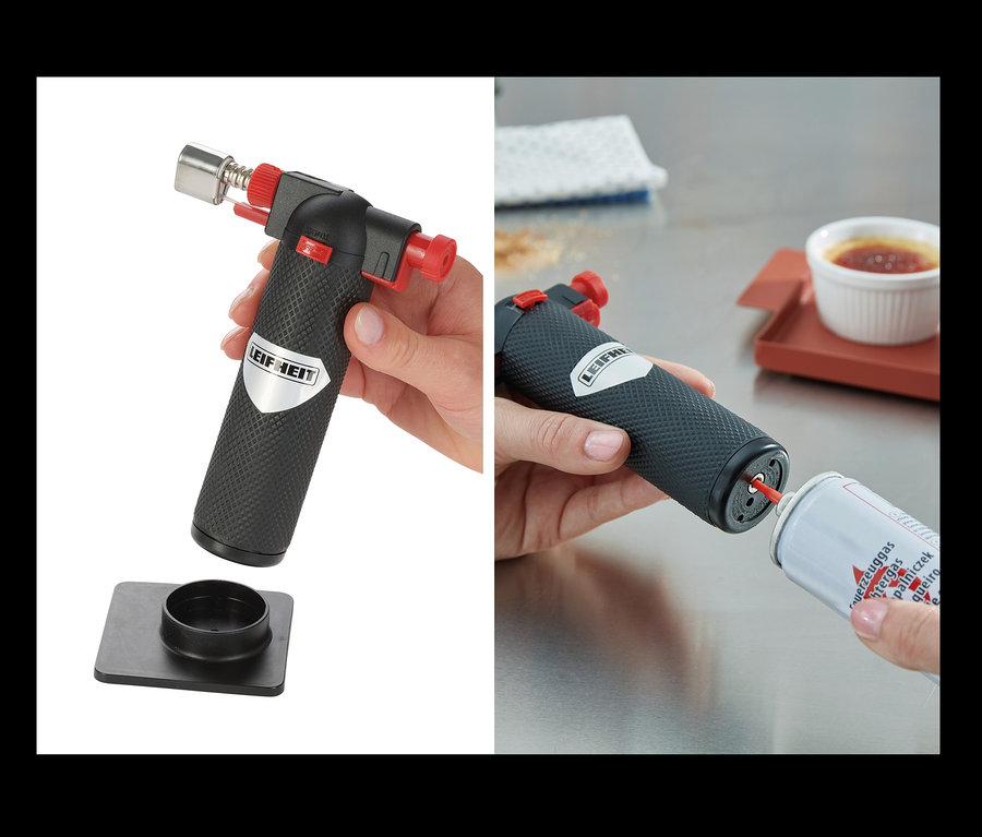 Eine Hand hält einen Gourmet-Brenner und platziert ihn auf einem schwarzen Sockel. Eine andere Hand befüllt einen Gourmet-Brenner. Im Hintergrund befindet sich eine Crème brûlée.