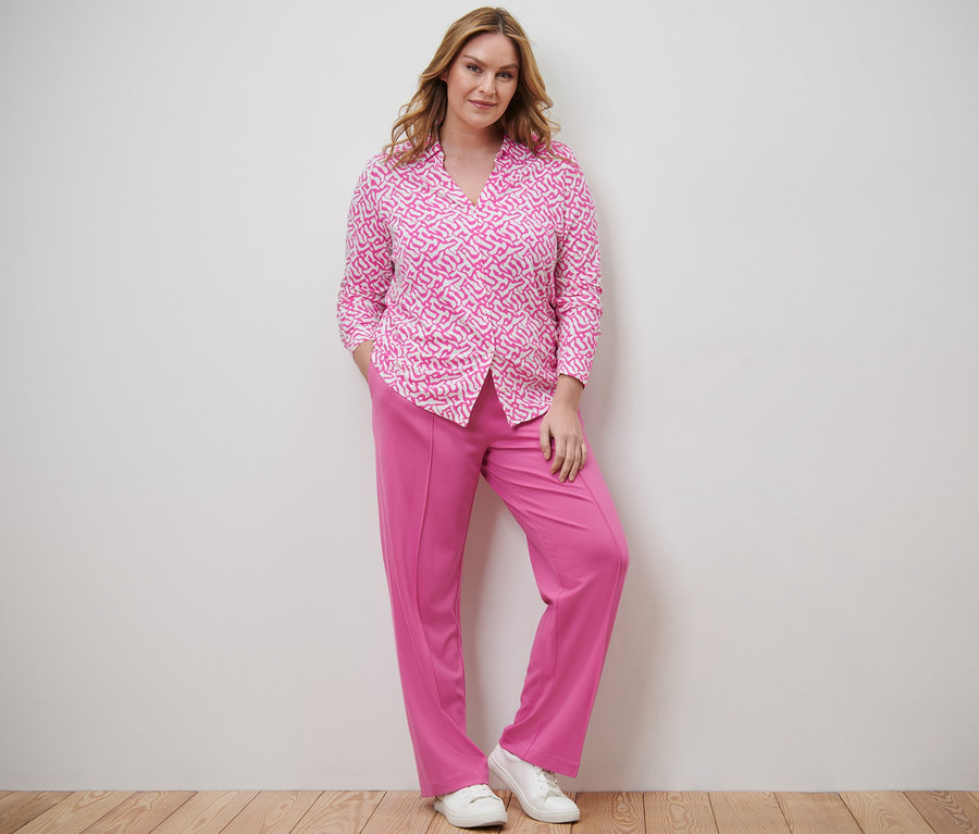 Frau posiert in Blusenshirt mit Knopfleiste und Jerseyhose mit Biese.