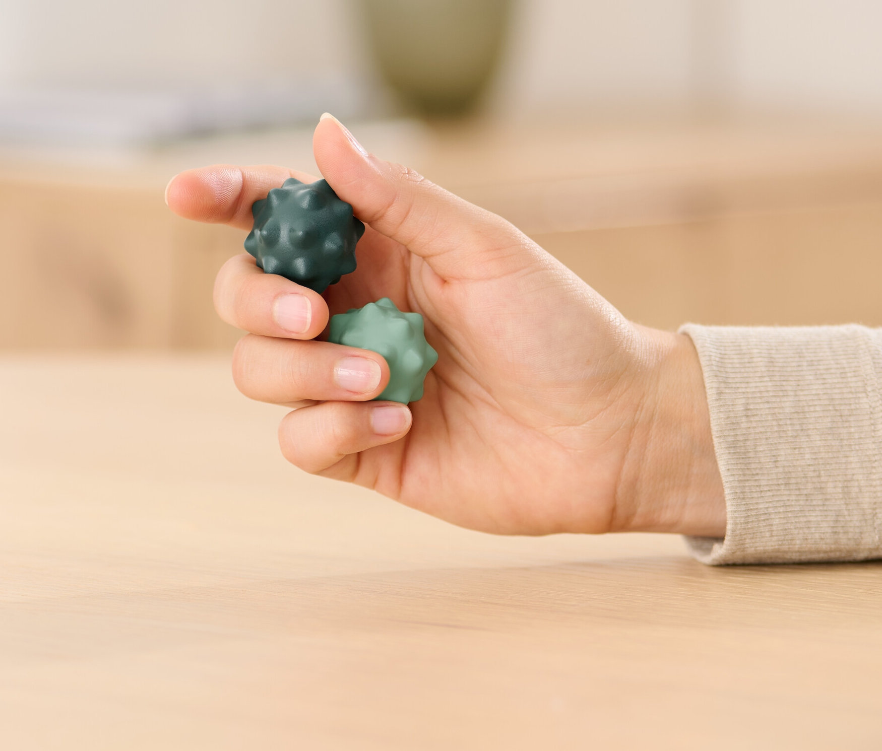 Eine Frau hält zwei Qi-Gong-Fingergymnastikkugeln in der Hand, eine dunkelgrün und eine hellgrün.