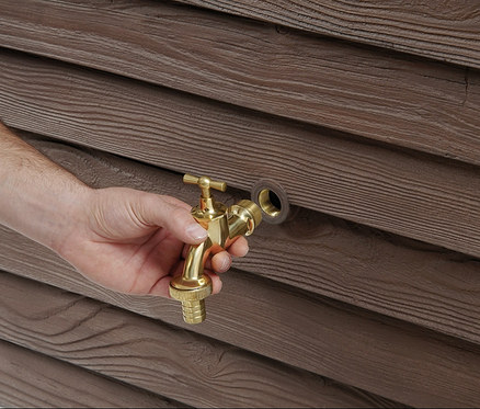 Eine Hand montiert einen Messinghahn an einem Garantia Wandtank-Komplett-Set »Woody«, ca. 350 l, darkwood.
