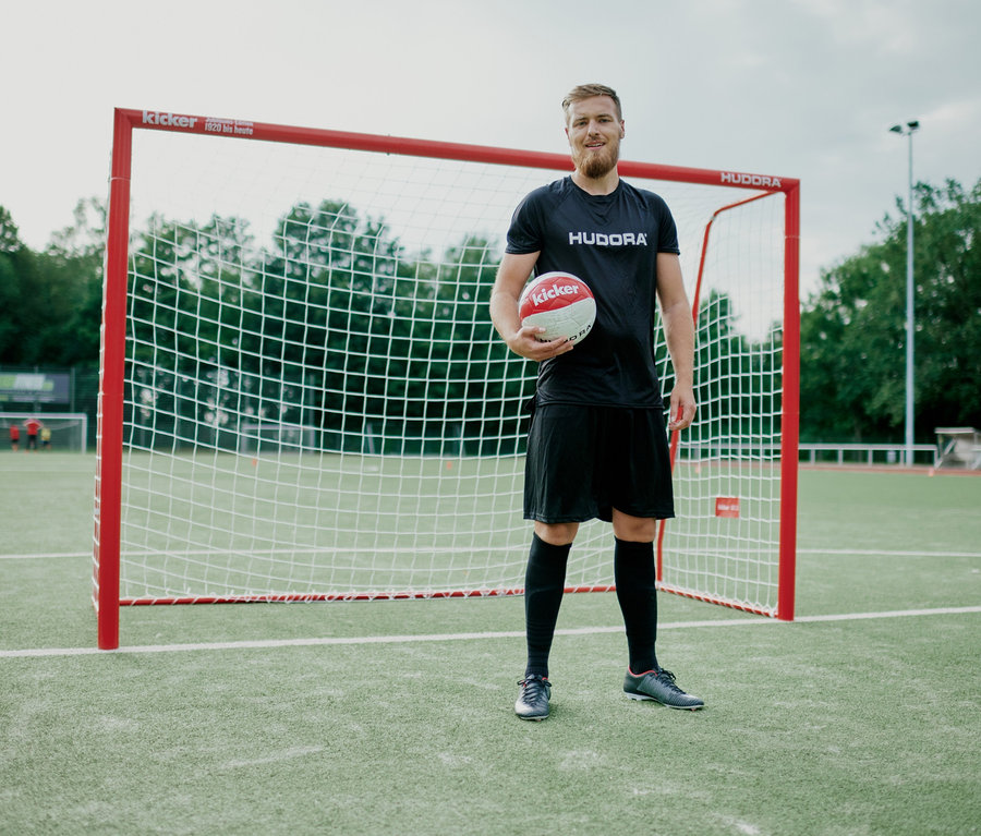 Mann hält einen Fußball vor einem HUDORA-Fußballtor Expert 300 "kicker-Edition".
