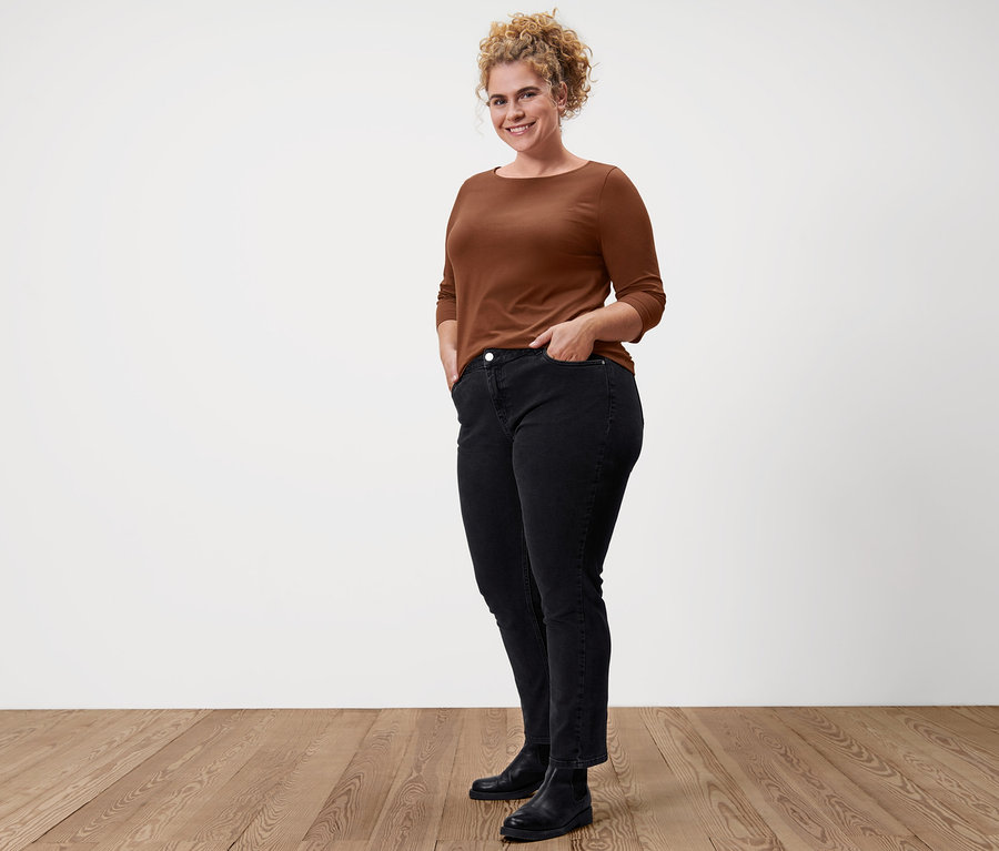 Frau posiert in cognacfarbenem Shirt mit 3/4-Arm, schwarzen Straight-Denim »Fit Juna« und Lederboots.