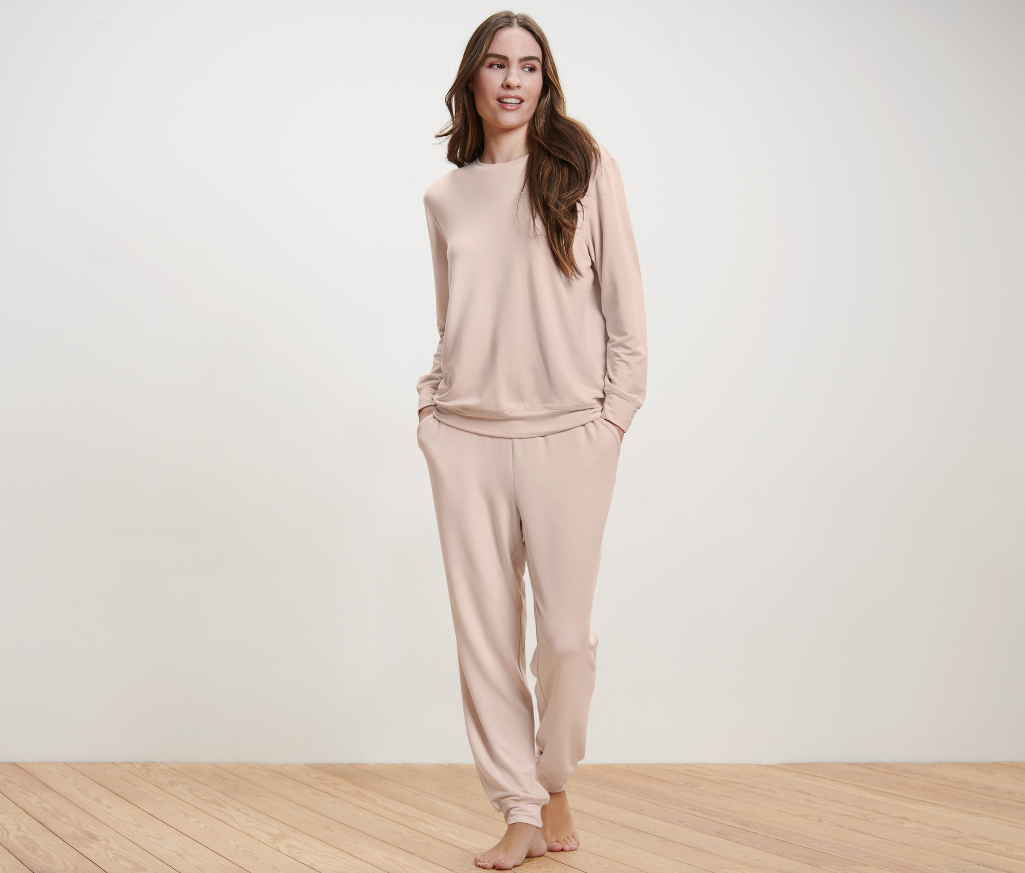 Frau posiert in einem cremefarbenen Hausanzug.