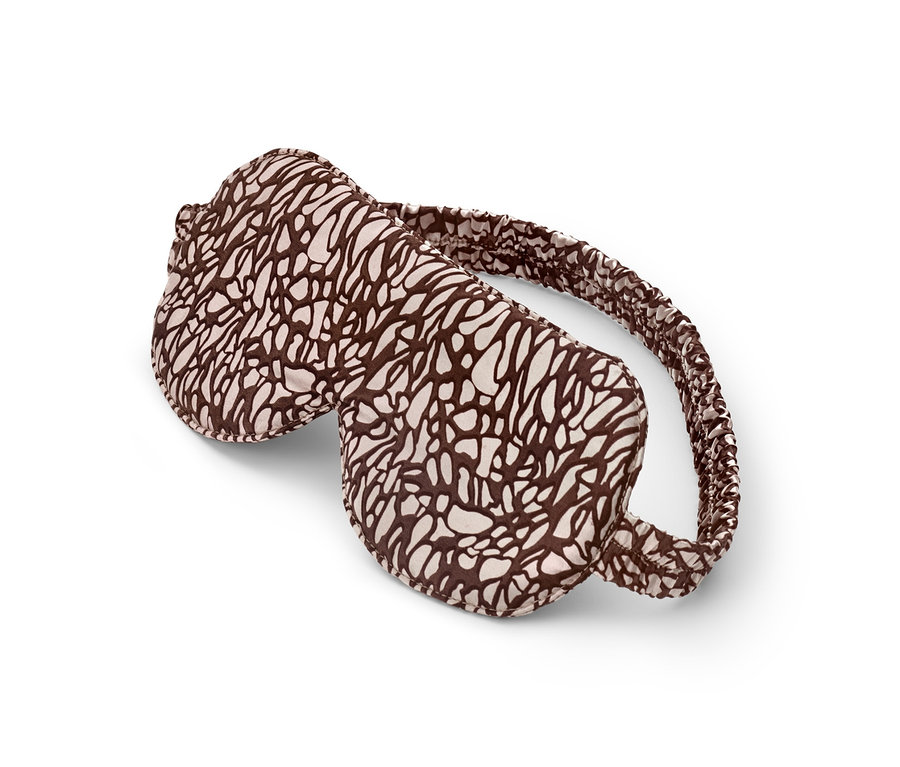 Eine braun-cremefarbene Schlafmaske liegt auf einem weißen Hintergrund.