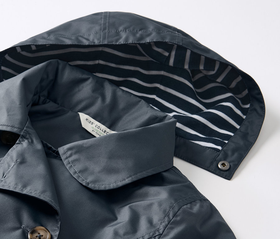Detailansicht eines Kinder-Allwetter-Trenchcoats mit Kapuze mit blau-weißen Streifen.